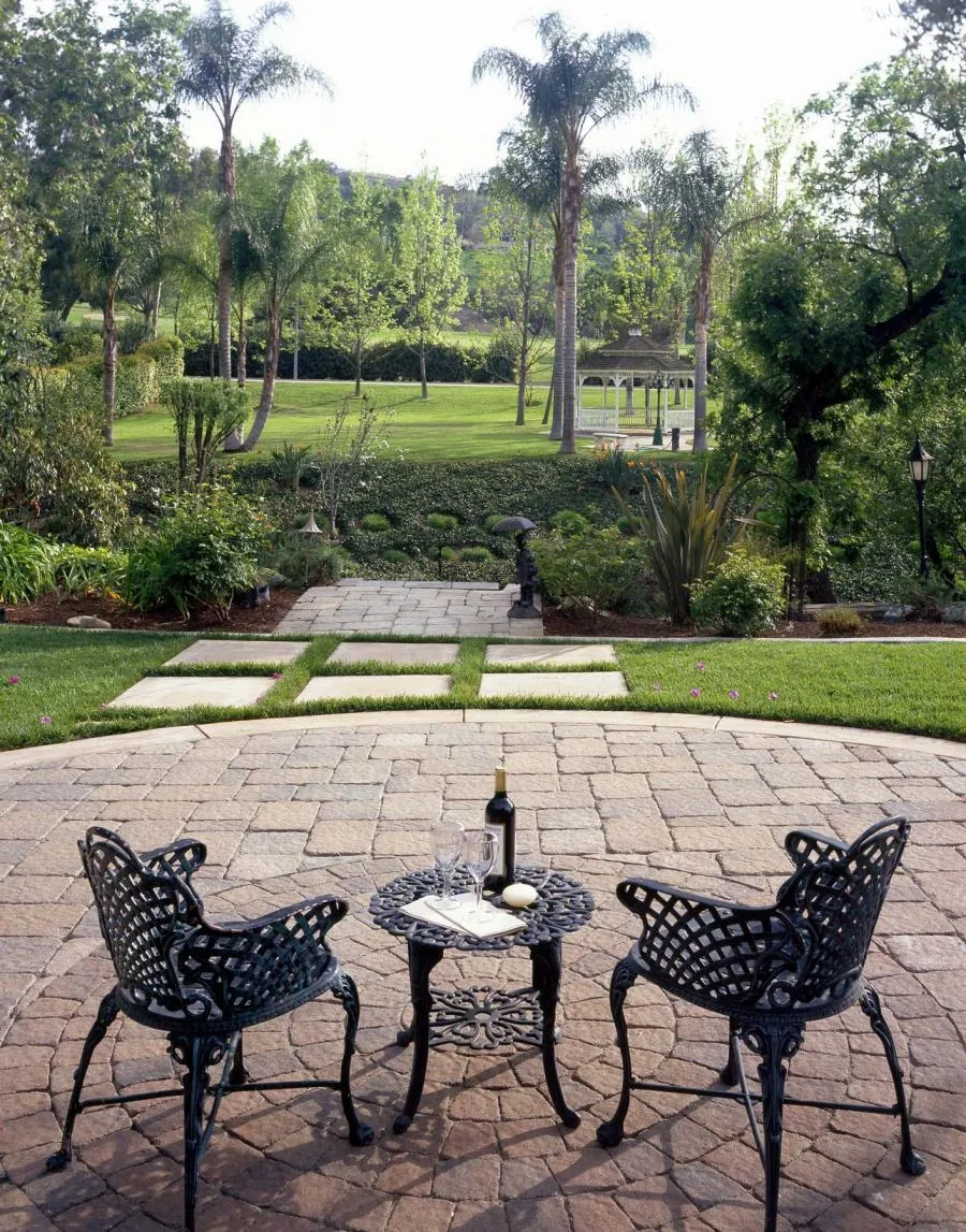 Picture of In a tranquil garden setting, two ornate chairs and a table invite moments of quiet reflection, showcasing Black Diamond Paver Stones & Landscape, Inc.'s commitment to quality outcomes. Copyright ©2025 Diamond Certified Resource. - Black Diamond Paver Stones & Landscape, Inc.