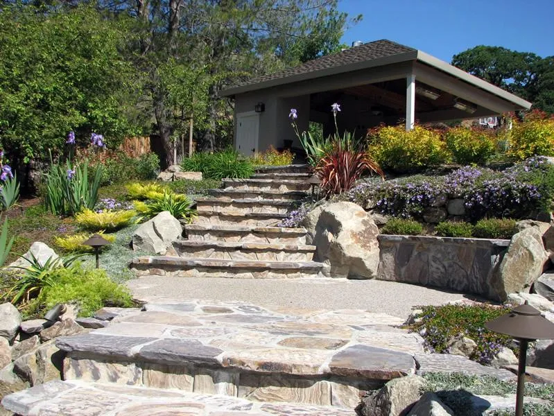  Stone steps with surrounding plants and a small pavilion in a landscaped garden.