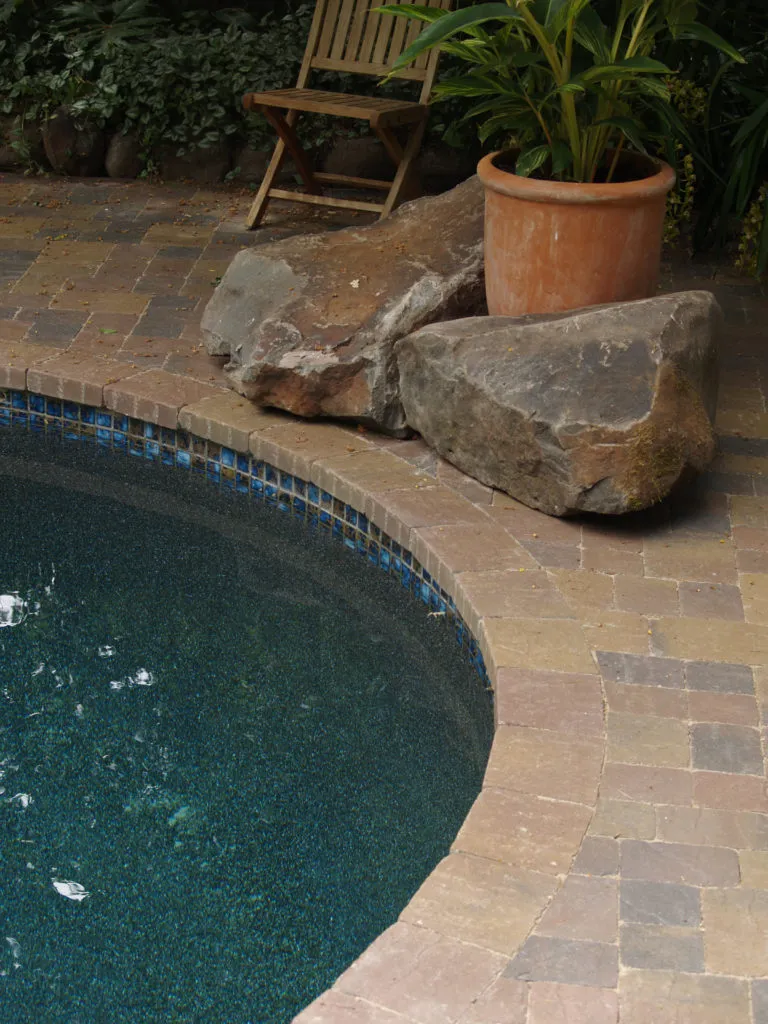 Picture of A serene corner by the pool features expertly laid stone pavers and natural elements, harmonizing with the lush surroundings. The Legacy Paver Groupâ€™s focus on quality outcomes is evident here. Copyright ©2025 Diamond Certified Resource

 - The Legacy Paver Group