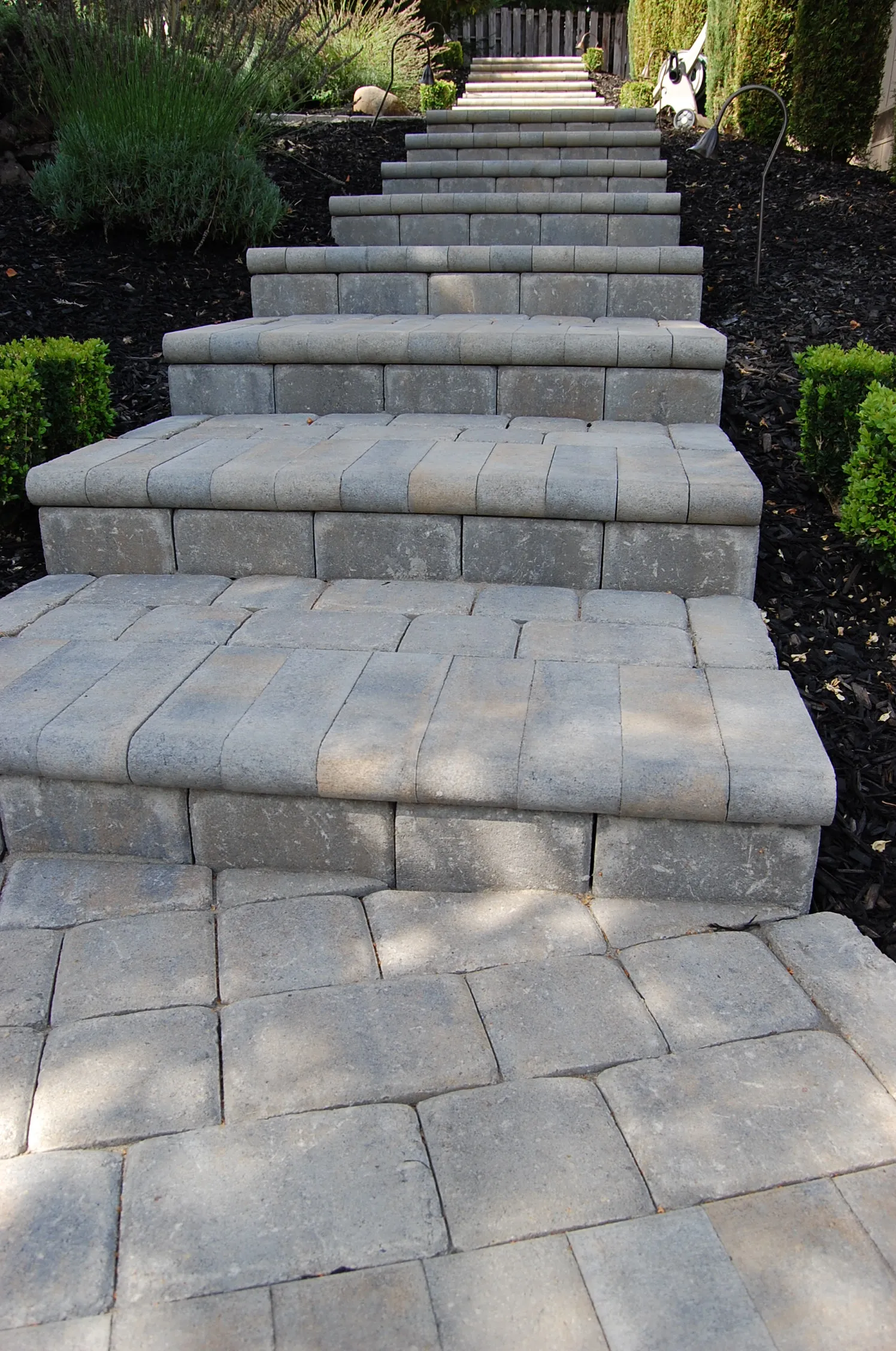 Picture of A meticulously crafted stone stairway leads through a well-manicured garden, exemplifying The Legacy Paver Group's focus on quality outcomes. Recognized for expertise and quality. Copyright ©2025 Diamond Certified Resource - The Legacy Paver Group