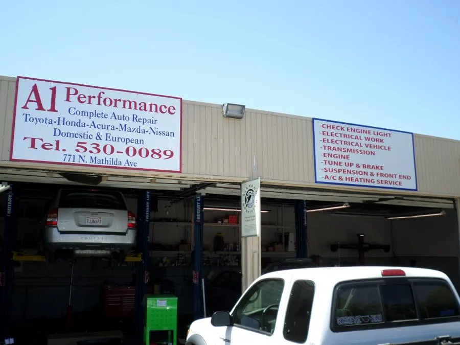  Car on lift in auto repair shop with signage for A1 Performance Auto Repair, detailing services offered.