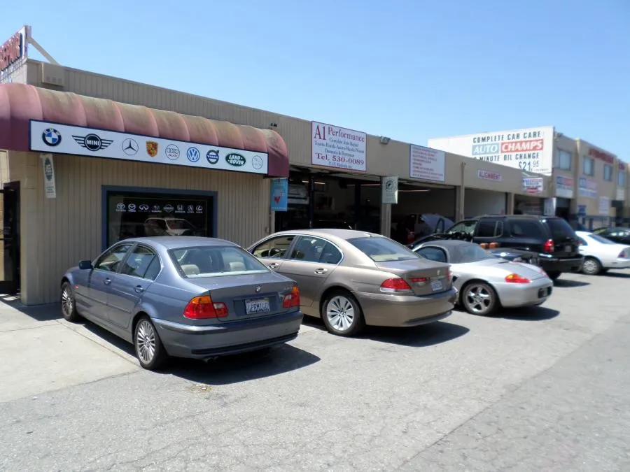 Several cars parked outside A1 Performance Auto Repair, with various brand logos displayed above the entrance on a sunny day.