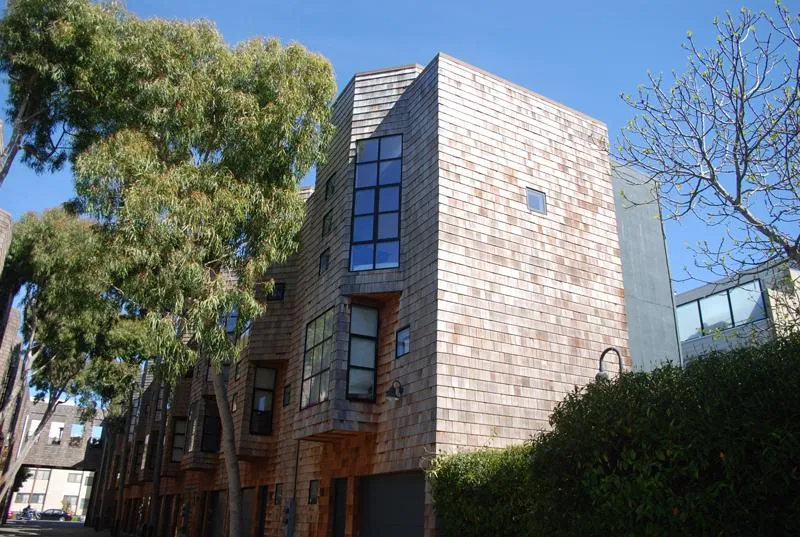 Picture of The sun casts gentle shadows on the shingled facade of a residential building, a testament to Ben's Roofing, Inc.'s commitment to quality outcomes. The building's modern design harmonizes with its natural surroundings, reflecting the company’s high customer satisfaction ratings. Copyright ©2025 Diamond Certified Resource. - Ben's Roofing, Inc.