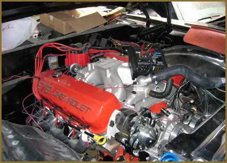  Close-up of a Chevrolet engine with red valve covers and visible wiring, installed in a vehicle's engine bay.