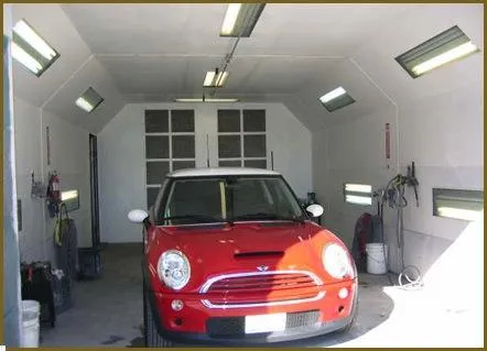  A red car parked inside a brightly lit garage with tools and equipment along the walls.