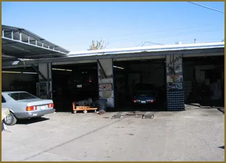 A car repair garage with cars inside open bays, surrounded by tools and automotive equipment.