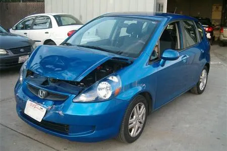  Blue Honda car with the hood open in a repair shop parking area, another car visible in the background.