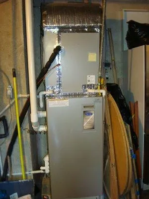  HVAC system installed in a utility room, featuring insulated ductwork and various plumbing connections around it.