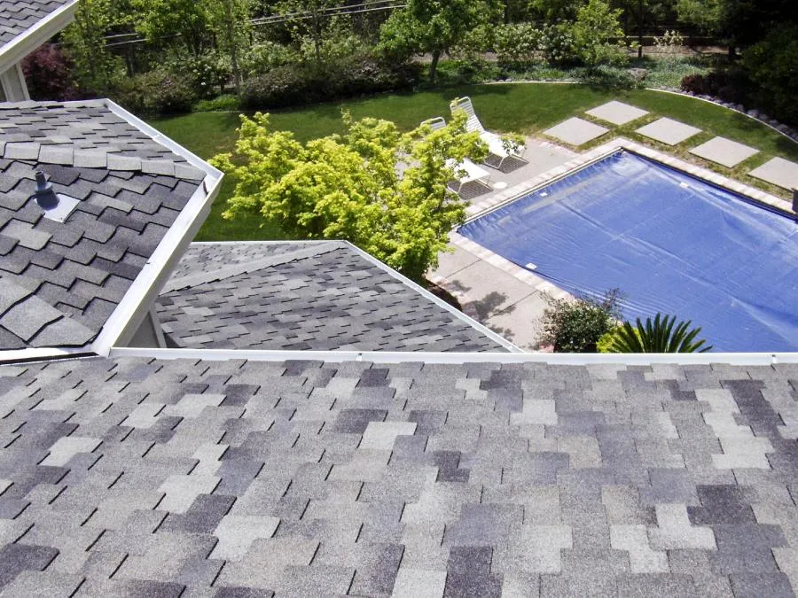  Overhead view of a shingled roof with a backyard pool and garden visible in the background.