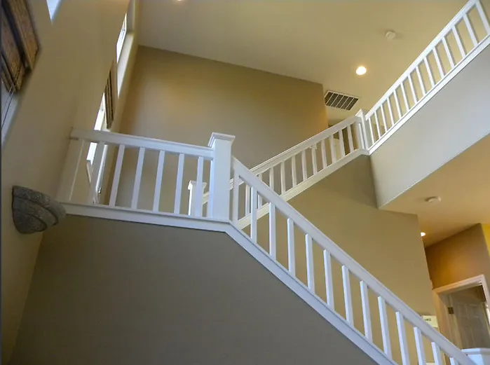 Interior view of a staircase with white railings and beige walls, lit by ceiling lights and natural light from windows. Interior view of a staircase with white railings and beige walls, lit by ceiling lights and natural light from windows.