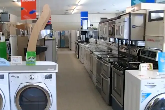 Interior of an appliance store with rows of stoves, washers, and other appliances displayed. Bright lighting and clear aisle visible. Interior of an appliance store with rows of stoves, washers, and other appliances displayed. Bright lighting and clear aisle visible.