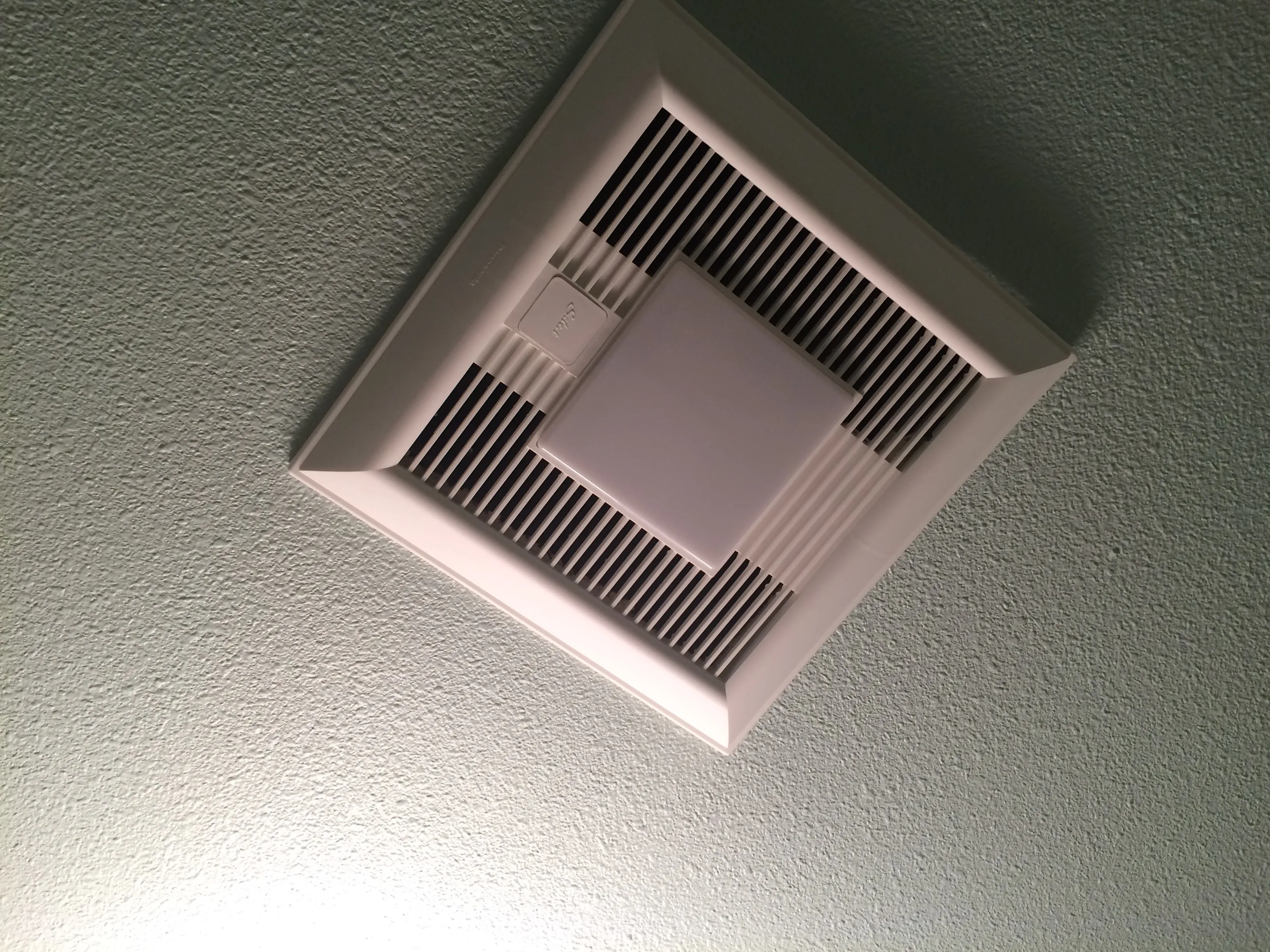 Close-up of a white ceiling vent with square grille against a textured ceiling. Close-up of a white ceiling vent with square grille against a textured ceiling.