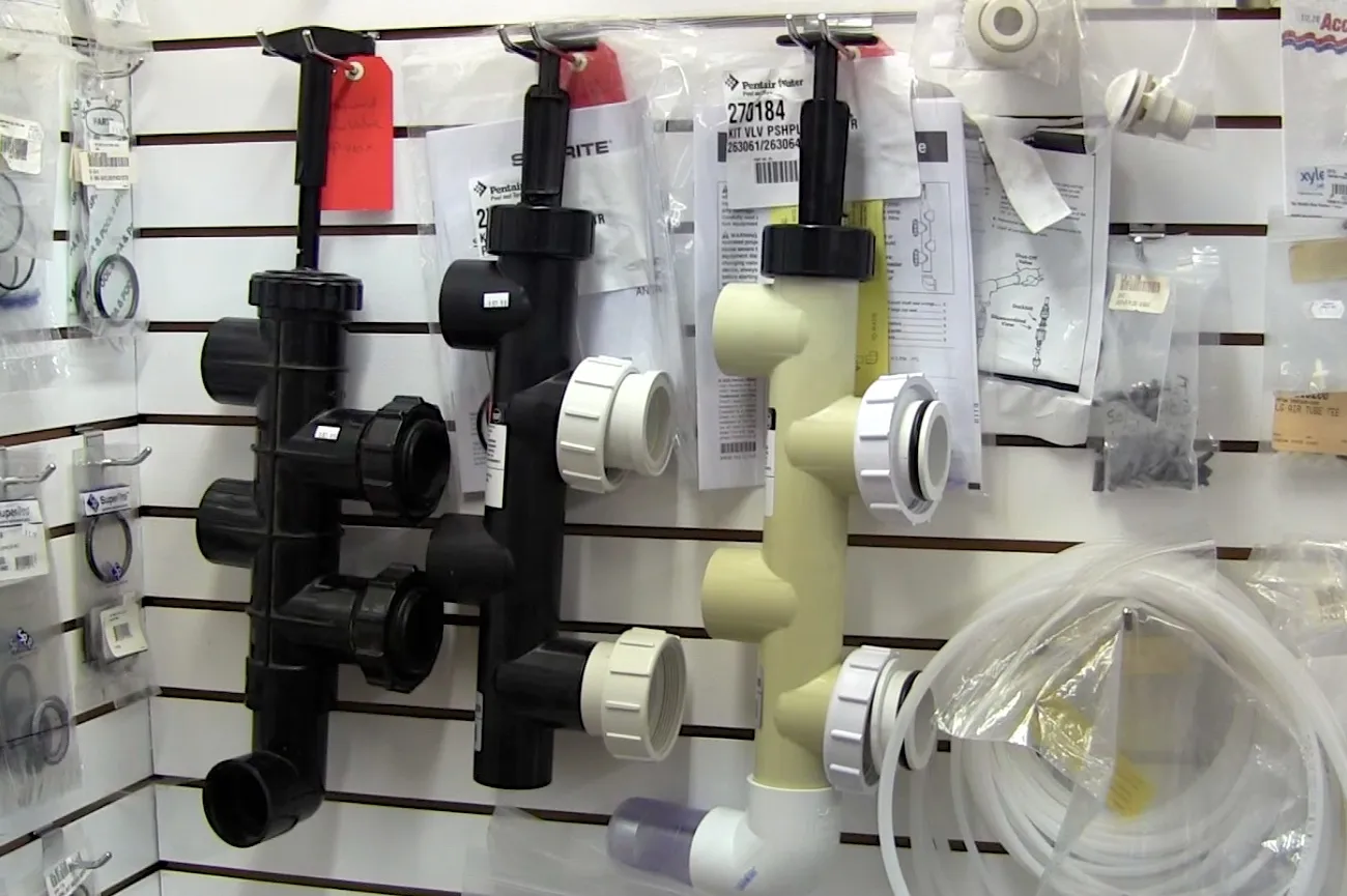 Various pool and spa plumbing components, including pipes and fittings, are organized on a wall display with related accessories in plastic bags. Various pool and spa plumbing components, including pipes and fittings, are organized on a wall display with related accessories in plastic bags.