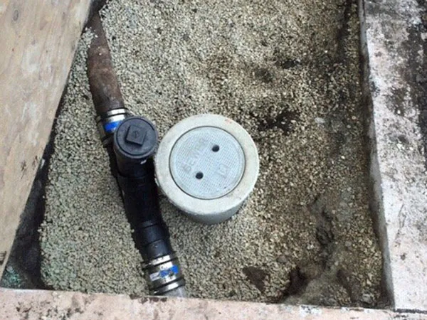 Sewer cleanout installation in progress, with a white cap surrounded by gravel and a black pipe connected to it. Sewer cleanout installation in progress, with a white cap surrounded by gravel and a black pipe connected to it.