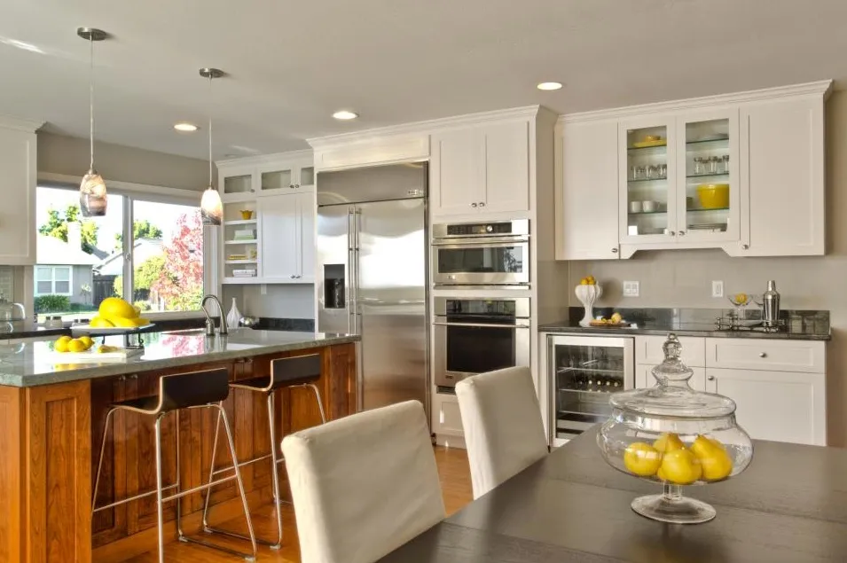 Modern kitchen with white cabinets, stainless steel appliances, and island. Lemons on table and counter. Modern kitchen with white cabinets, stainless steel appliances, and island. Lemons on table and counter.