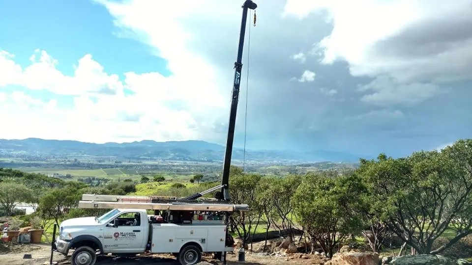 Picture of Amidst a serene landscape, a McLean & Williams, Inc. service truck stands poised, its towering crane ready for action. This scene reflects the companyâ€™s commitment to quality outcomes and high customer satisfaction. Copyright ©2025 Diamond Certified Resource

 - McLean & Williams, Inc.