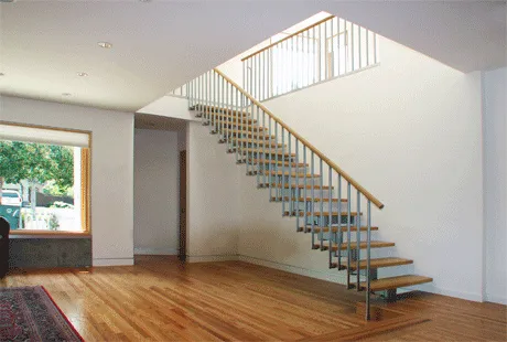 Spacious empty room with a modern floating staircase and wooden floors. Natural light enters through a large window, illuminating the minimalist interior. Spacious empty room with a modern floating staircase and wooden floors. Natural light enters through a large window, illuminating the minimalist interior.