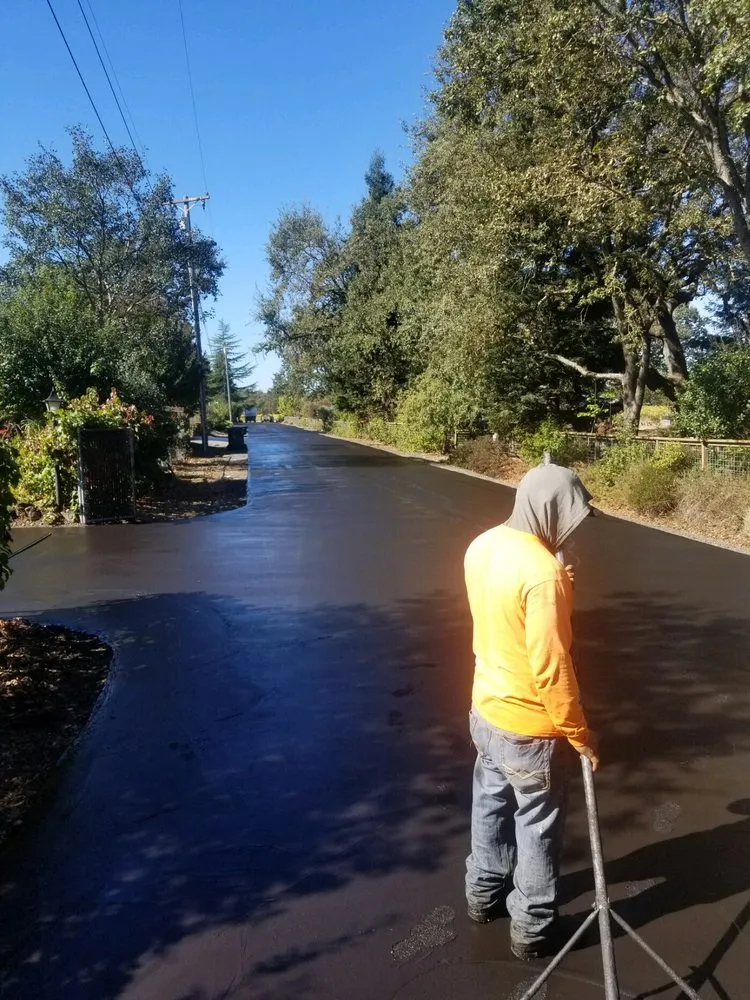 Picture of A worker in a bright orange shirt methodically smooths a fresh layer of asphalt under a clear blue sky, exemplifying Jackson's Paving & Equipment Rentals, Inc.'s focus on quality outcomes. Copyright ©2025 Diamond Certified Resource. - Jackson's Paving & Equipment Rentals, Inc.