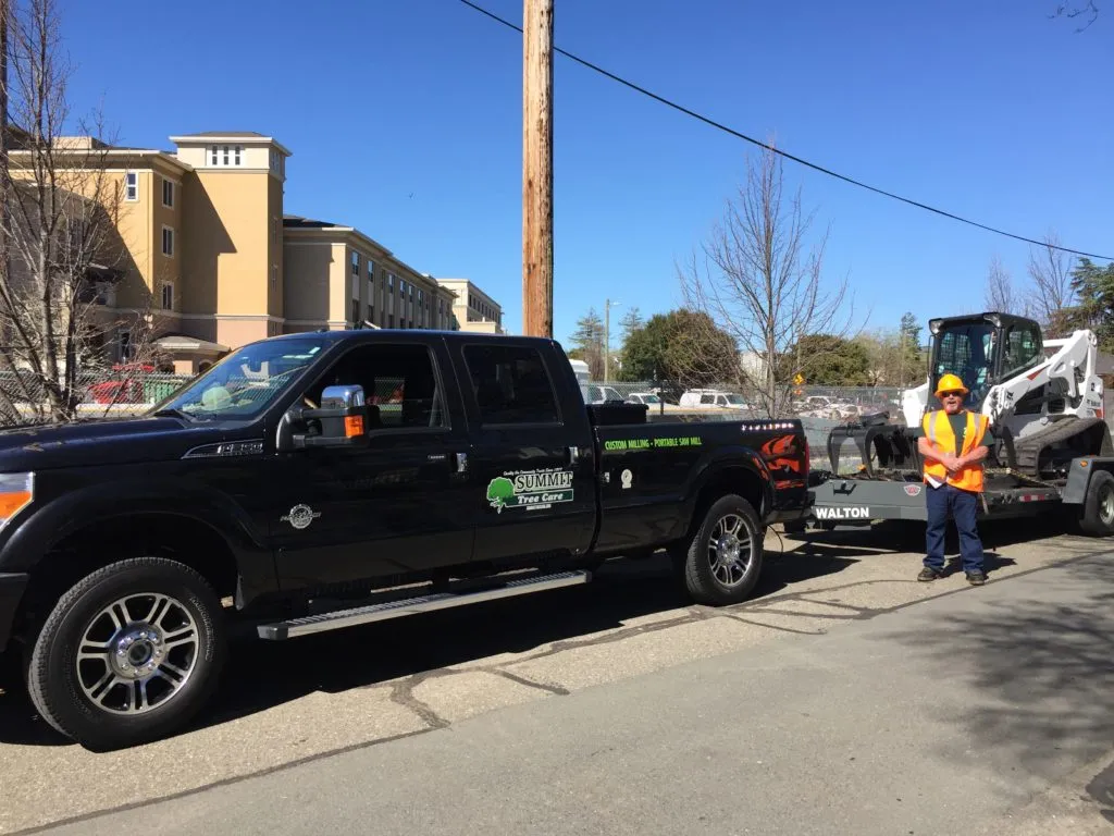 Picture of A Summit Tree Care truck, loaded with essential equipment, pauses mid-task as a worker in high-visibility gear oversees the operation. The company's commitment to quality outcomes is evident in every detail. Copyright ©2025 Diamond Certified Resource

 - Summit Tree Care
