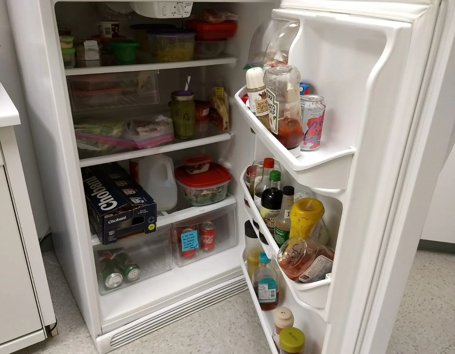 Open refrigerator with assorted food items on shelves and door, including containers, drinks, and condiments. Open refrigerator with assorted food items on shelves and door, including containers, drinks, and condiments.