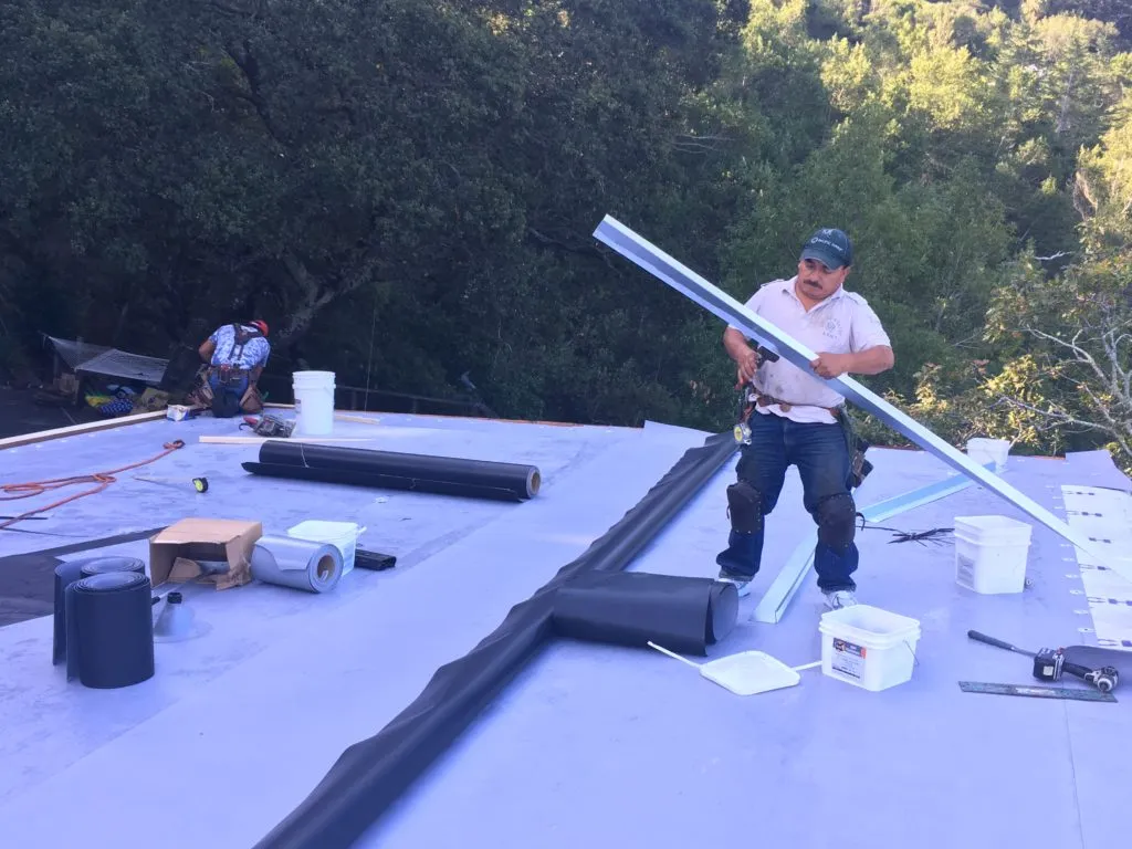 Picture of  A focused roofer stands amid tools and materials, carefully measuring a piece for installation on a serene rooftop surrounded by leafy trees. Capstone Roofing, Inc. consistently achieved a Highest in Quality rating, ensuring each project meets exacting standards. Copyright ©2025 Diamond Certified Resource.

 - Capstone Roofing, Inc.