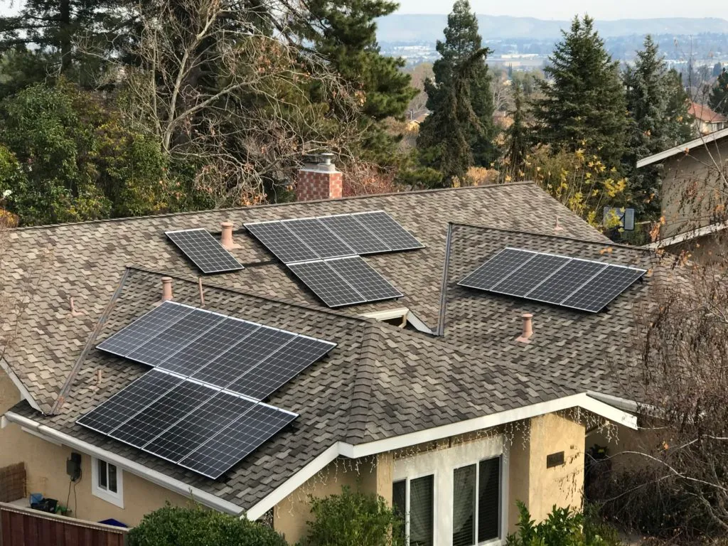 Rooftop of a house with multiple solar panels installed amidst surrounding trees. Rooftop of a house with multiple solar panels installed amidst surrounding trees.