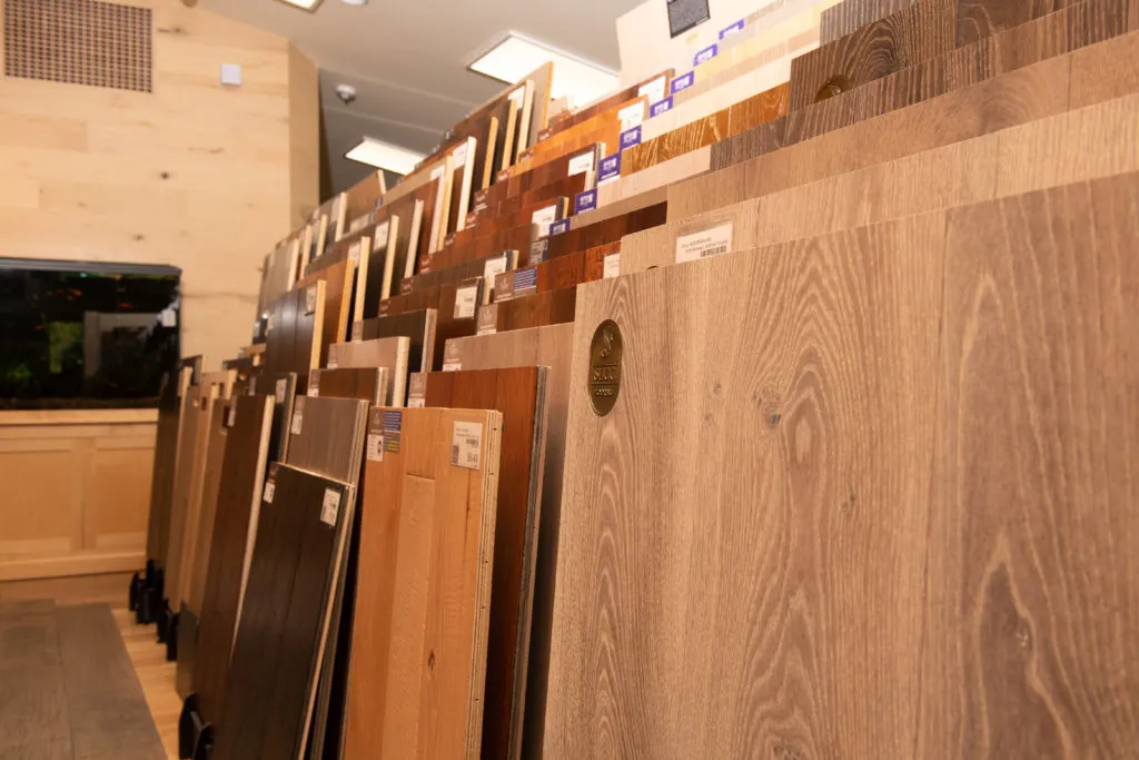 Rows of wooden flooring samples displayed in a showroom, showcasing various colors and textures. Rows of wooden flooring samples displayed in a showroom, showcasing various colors and textures.
