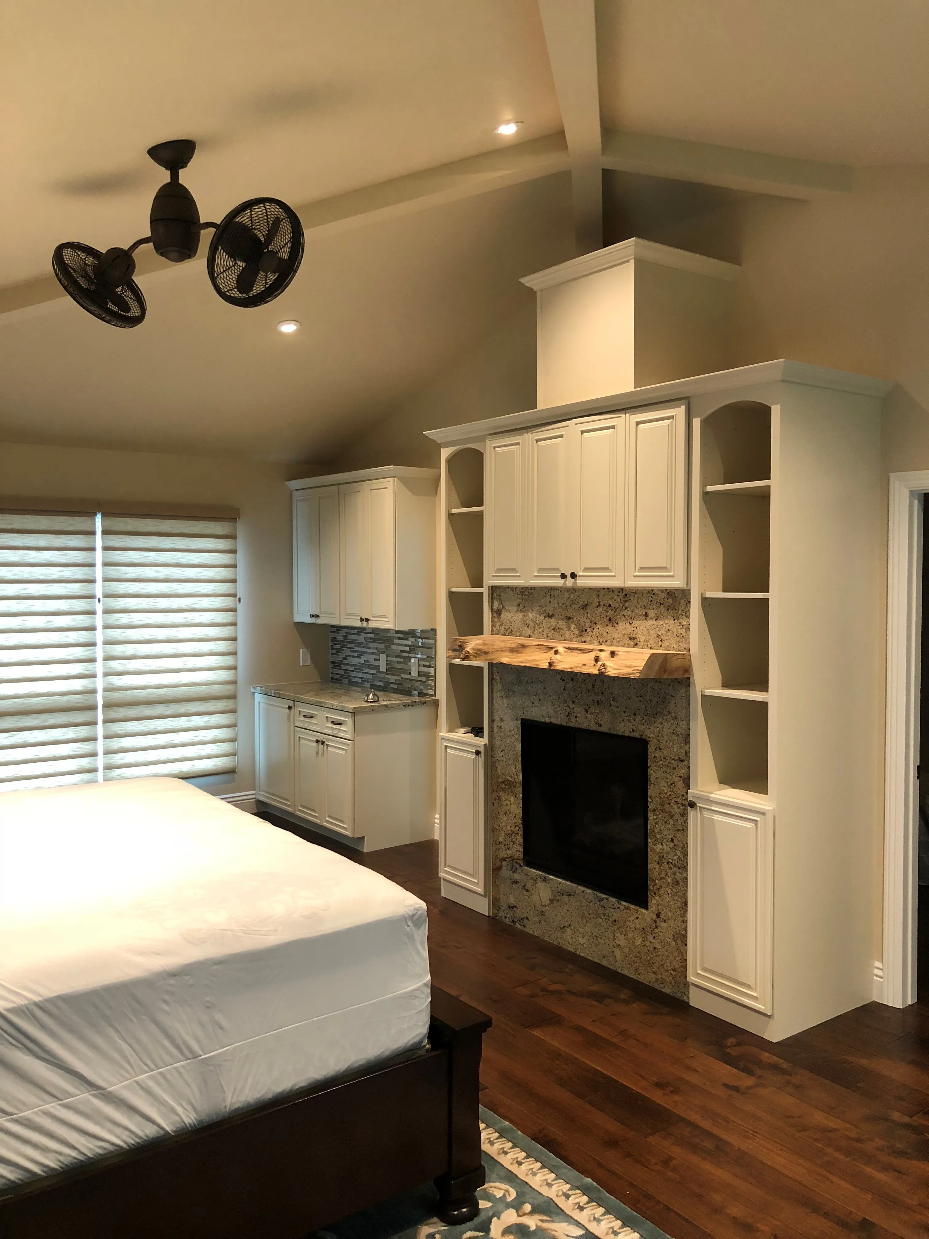 Picture of  Evenich Construction, Inc. has designed a serene bedroom space featuring a custom fireplace with elegant cabinetry and natural wood mantel, reflecting its focus on quality outcomes. The polished hardwood floors and modern ceiling fan add sophistication to the tranquil setting. Copyright ©2025 Diamond Certified Resource.

 - Evenich Construction, Inc.