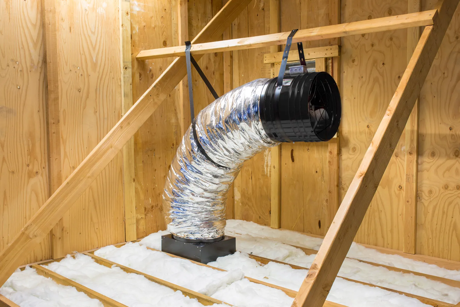 Insulated attic with shiny ductwork suspended by metal straps, surrounded by wooden beams and walls. Insulated attic with shiny ductwork suspended by metal straps, surrounded by wooden beams and walls.