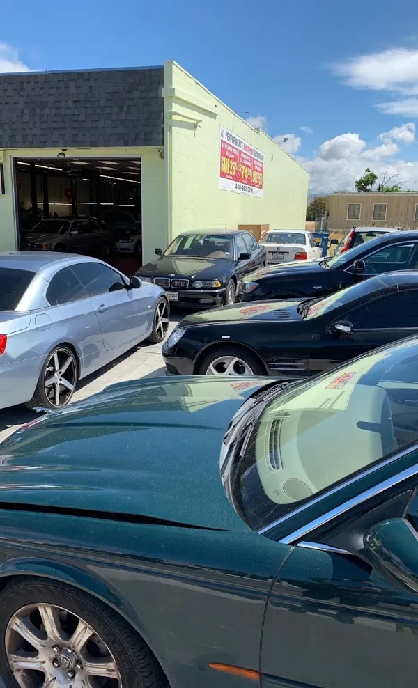  Several cars parked outside an auto repair shop under a clear blue sky. A sign on the building reads "A1 Performance Auto Repair."