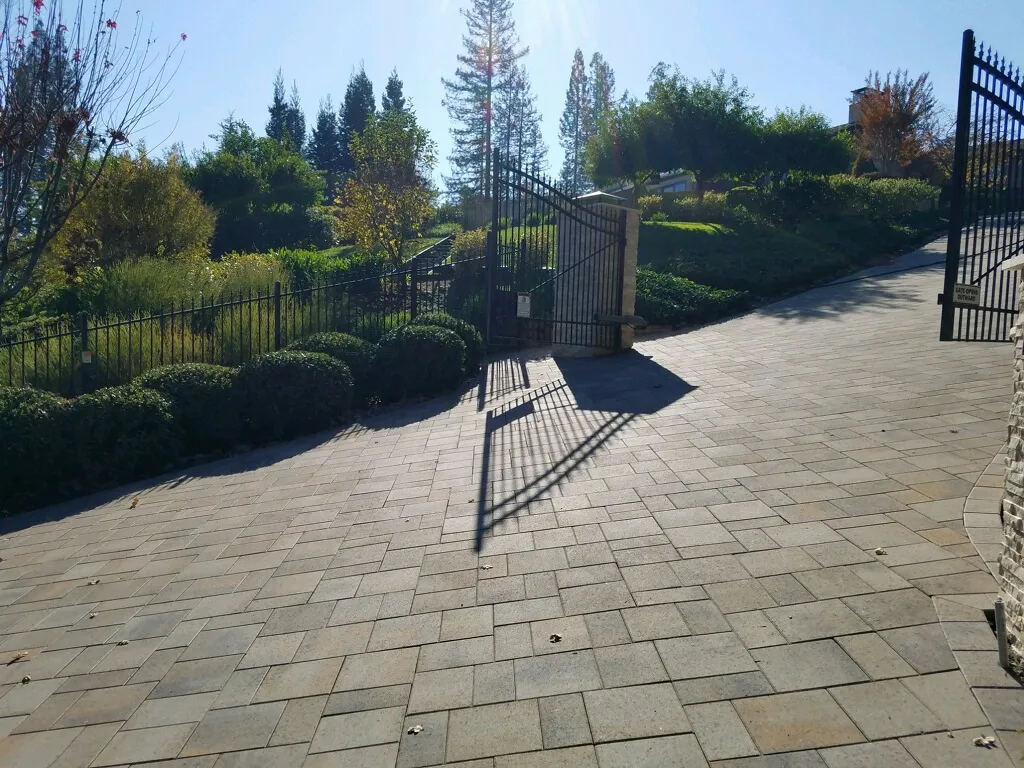Picture of Sunlight casts shadows over an intricately paved driveway leading to a gated entrance, a testament to The Legacy Paver Group's focus on quality outcomes. This serene path invites one to explore the lush surroundings beyond, embodying their consistent achievement of a Highest in Quality rating. Copyright ©2025 Diamond Certified Resource

 - The Legacy Paver Group