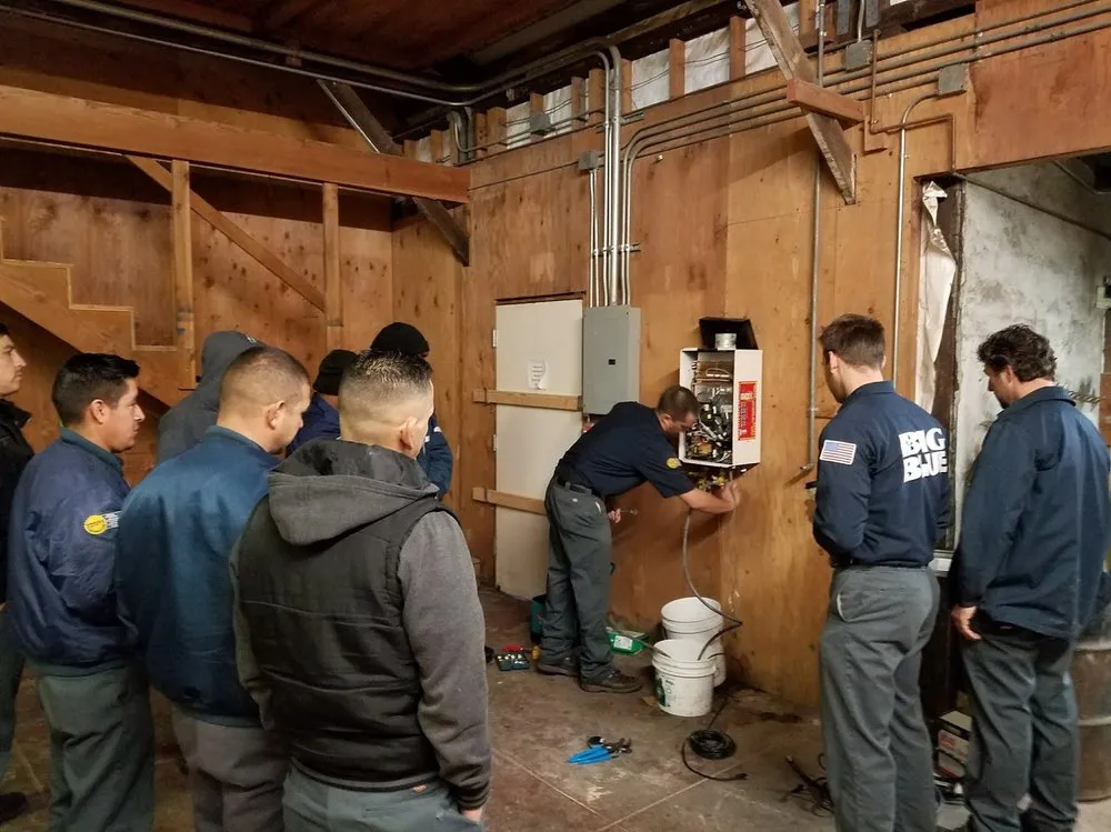 Picture of In a workshop, Big Blue Plumbing employees attentively observe a colleague while he expertly works on a control panel. The company consistently achieved a Highest in Quality rating, reflecting its dedication to superior training and expertise. Copyright ©2025 Diamond Certified Resource

 - Big Blue Plumbing