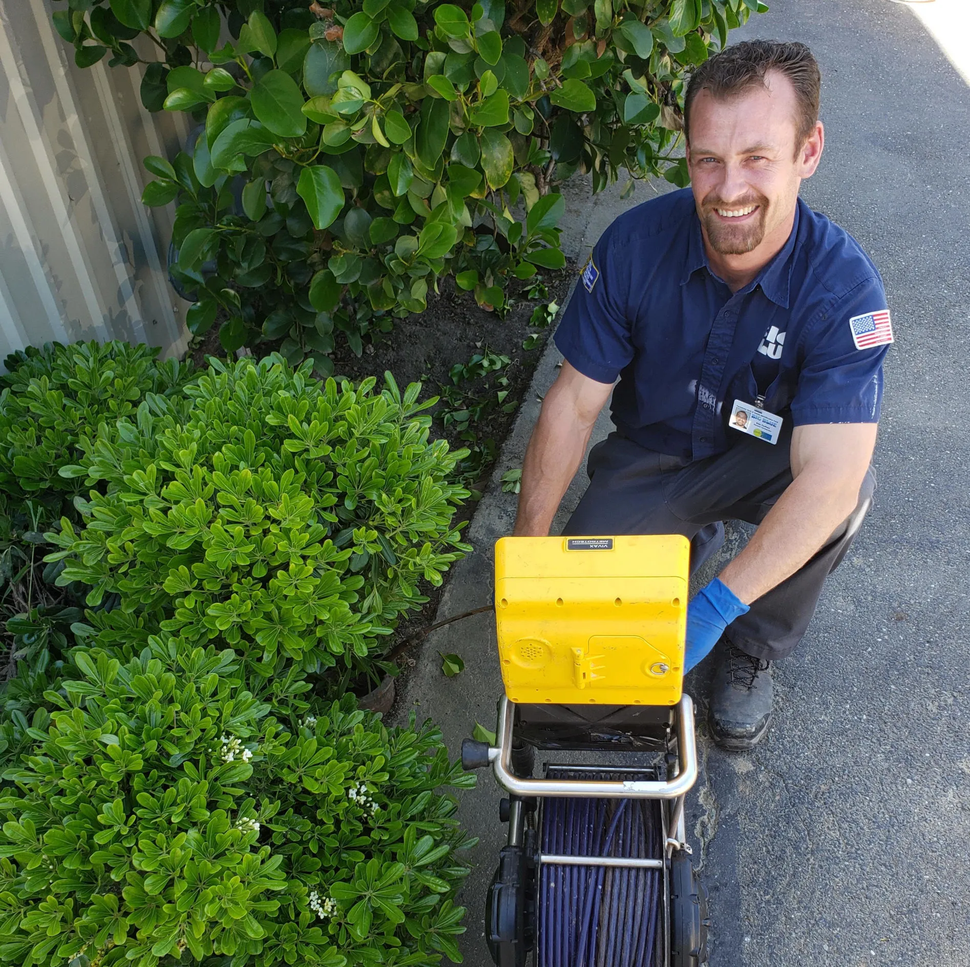 Picture of In a moment framed by greenery, a Big Blue Plumbing technician demonstrates their commitment to quality outcomes by expertly handling advanced plumbing equipment. The company's focus on quality is evident in every task. Copyright ©2025 Diamond Certified Resource - Big Blue Plumbing