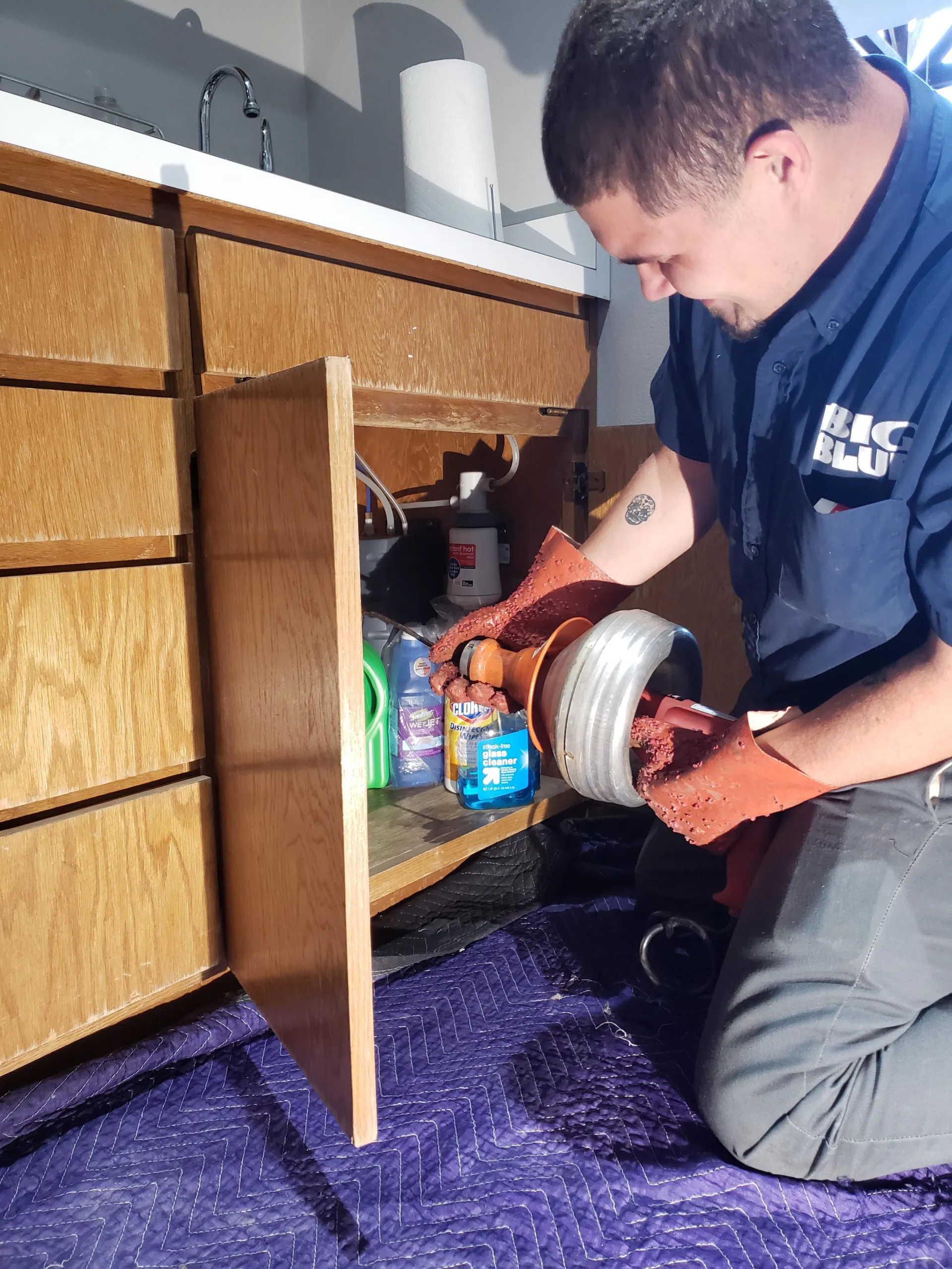 Picture of A Big Blue Plumbing technician meticulously inspects a pipe under a kitchen sink, embodying the companyâ€™s commitment to quality outcomes. Their attentive service ensures a smooth flow in every household. Copyright ©2025 Diamond Certified Resource

 - Big Blue Plumbing