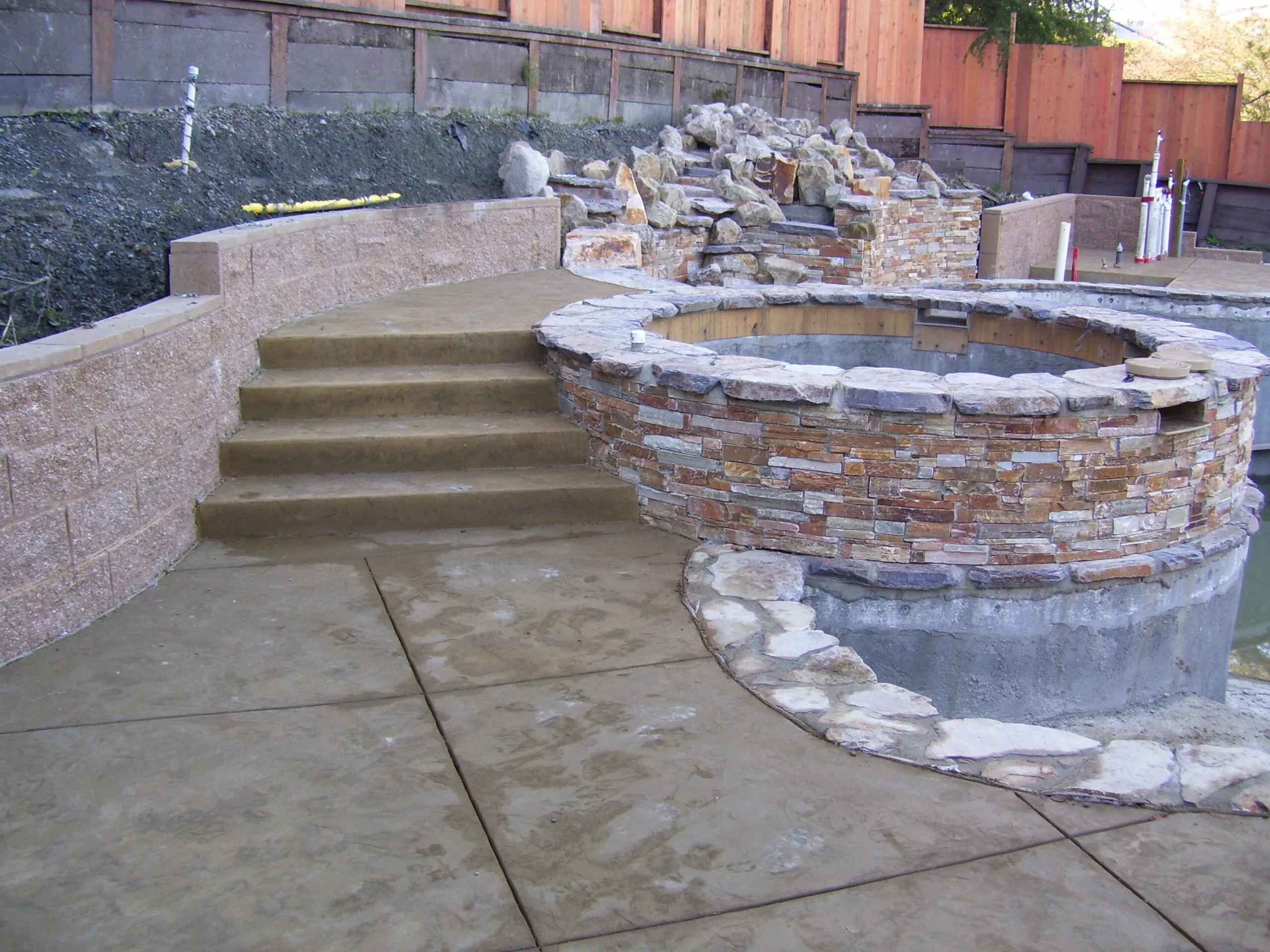 Picture of  A newly constructed stone and concrete staircase leads to a circular stone structure, showcasing Paradigm Concrete & Construction, Inc.'s focus on quality outcomes and craftsmanship. Copyright ©2025 Diamond Certified Resource.

 - Paradigm Concrete & Construction, Inc.