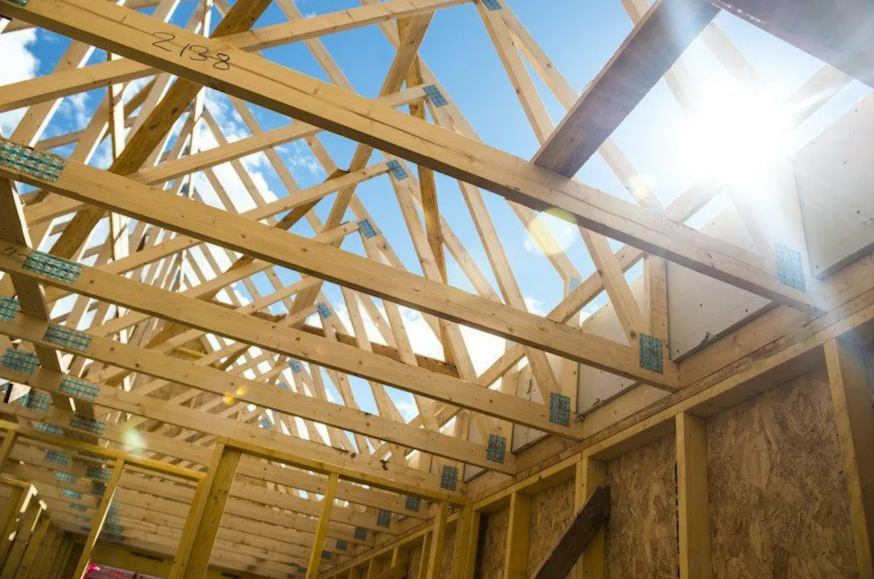 Wooden trusses of a construction project with sunlight streaming through, creating a pattern of light and shadow. Wooden trusses of a construction project with sunlight streaming through, creating a pattern of light and shadow.