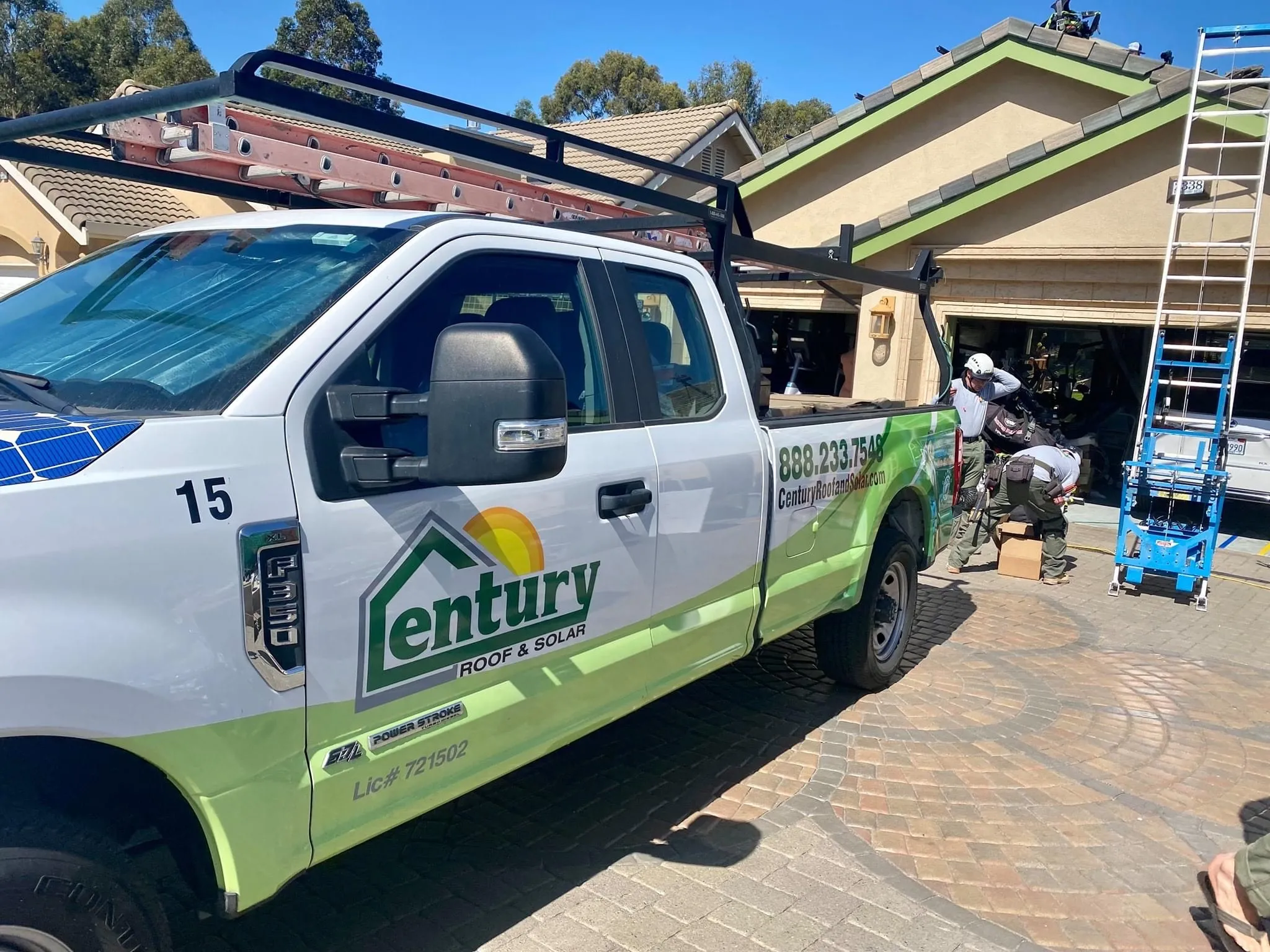  Century Roof and Solar truck parked in driveway with two workers preparing tools and equipment near a house. A ladder and rooftop activity are visible.