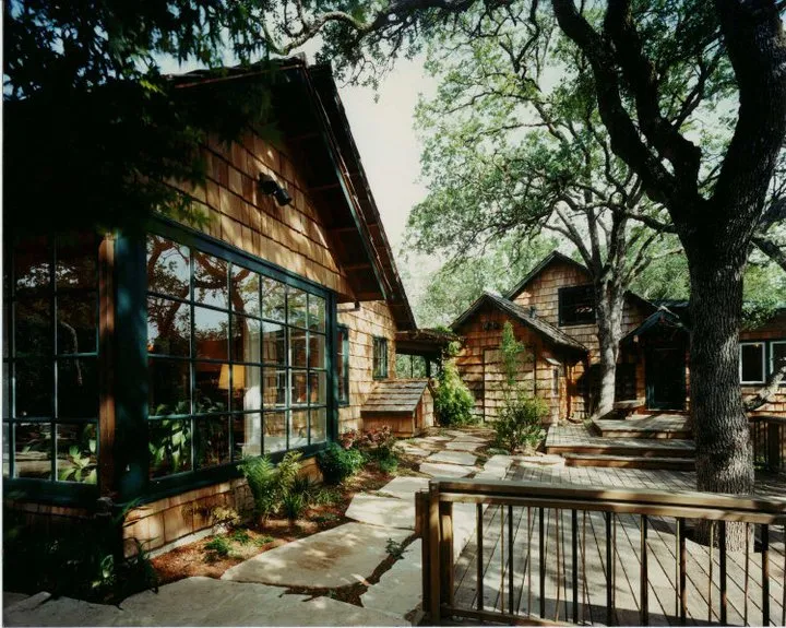 Rustic wooden structures surrounded by trees, with a paved stone walkway and large windows reflecting the greenery. Rustic wooden structures surrounded by trees, with a paved stone walkway and large windows reflecting the greenery.