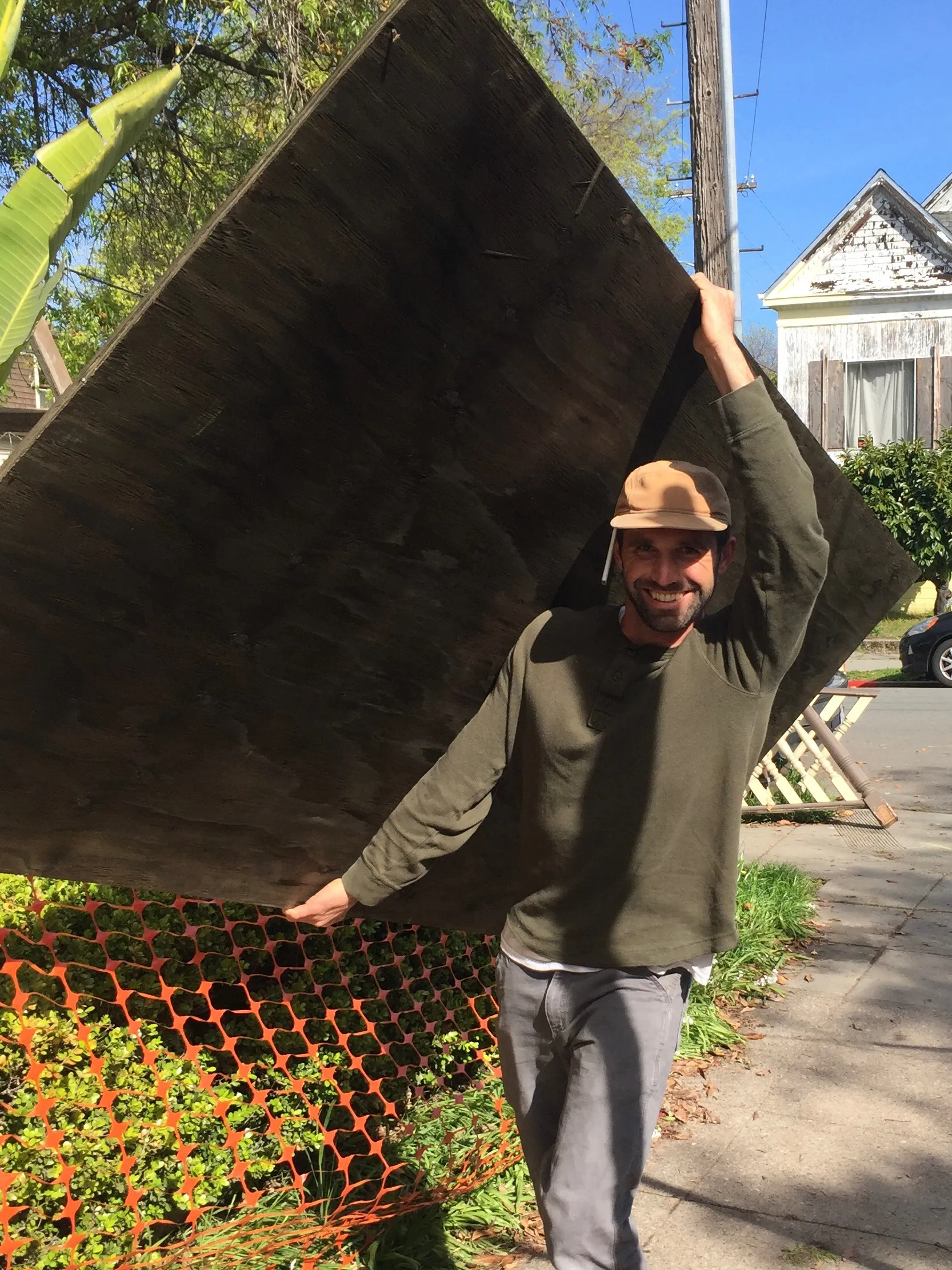 Picture of A worker carries a large wooden board on his shoulder, showcasing the hands-on expertise of Green Living Builders LLC. This image highlights the company's commitment to quality outcomes, reflecting their top-rated status for quality. Copyright ©2025 Diamond Certified Resource - Green Living Builders LLC