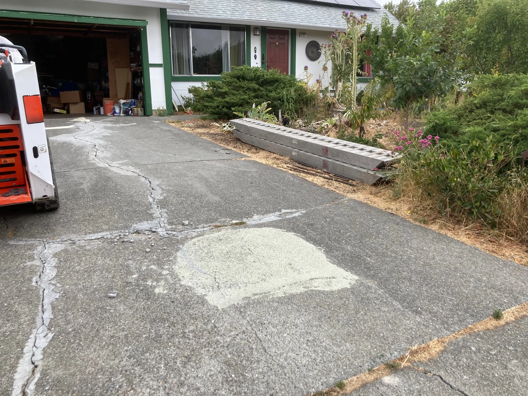Picture of A driveway shows fresh concrete patchwork, hinting at ongoing renovations by The Legacy Paver Group. Recognized for expertise and quality, they seamlessly blend repairs with existing surfaces. Copyright ©2025 Diamond Certified Resource - The Legacy Paver Group
