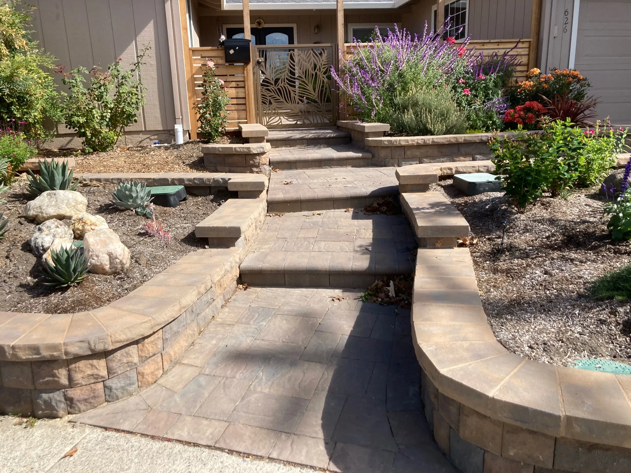 Picture of The Legacy Paver Group transforms a simple entrance into a welcoming pathway lined with vibrant flora and expertly laid stonework, highlighting both aesthetic appeal and careful craftsmanship. Recognized for their expertise and quality, they've created a harmonious blend of nature and design. Copyright ©2025 Diamond Certified Resource

 - The Legacy Paver Group