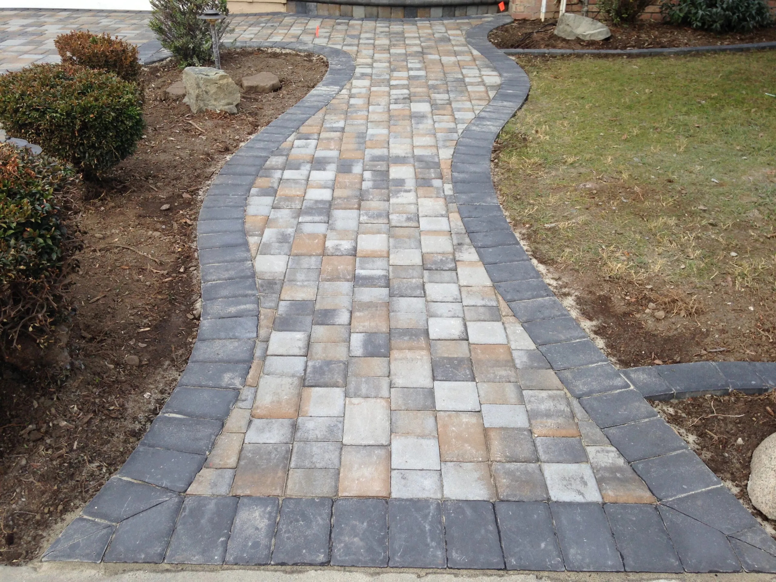 Picture of A meticulously crafted stone walkway meanders through a garden, showcasing Unique Pavers' commitment to quality outcomes. This expertly laid path exemplifies the companyâ€™s focus on high customer satisfaction ratings. Copyright ©2025 Diamond Certified Resource

 - Unique Pavers