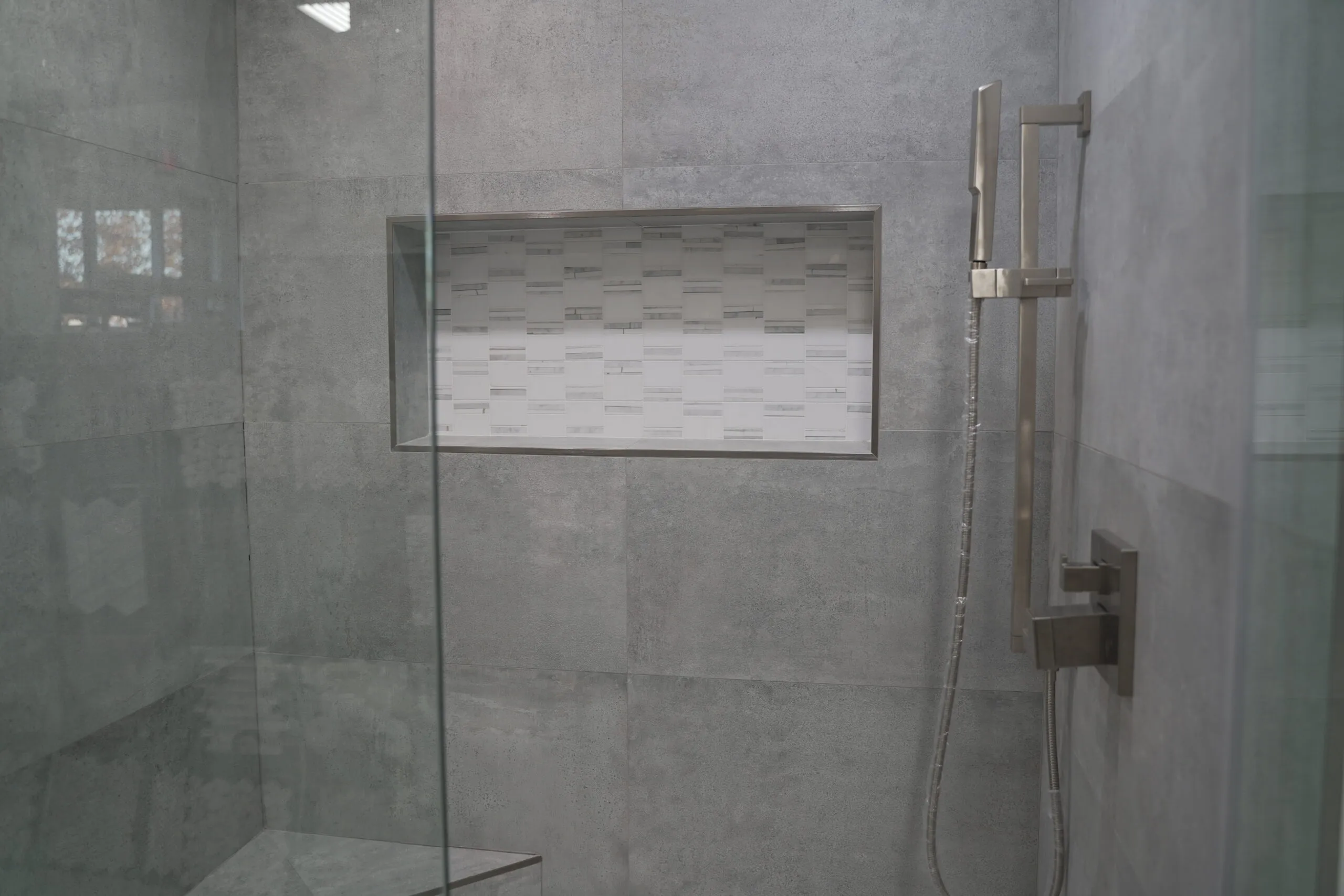 Picture of In a serene corner of a modern shower, sleek gray tiles frame a small niche, hinting at a dedication to detail. Today's Kitchen & Bath consistently achieves a Highest in Quality rating, transforming spaces with subtle elegance. Copyright ©2025 Diamond Certified Resource - Today's Kitchen & Bath