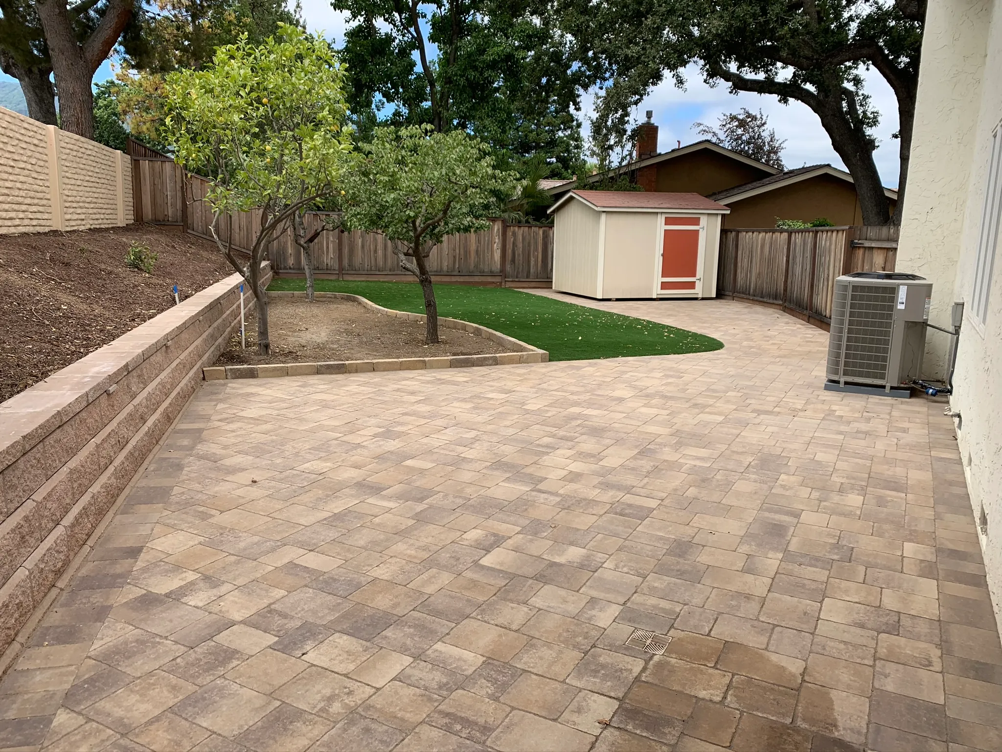 Brick patio with trees, a shed, an HVAC unit, and a wooden fence. Brick patio with trees, a shed, an HVAC unit, and a wooden fence.