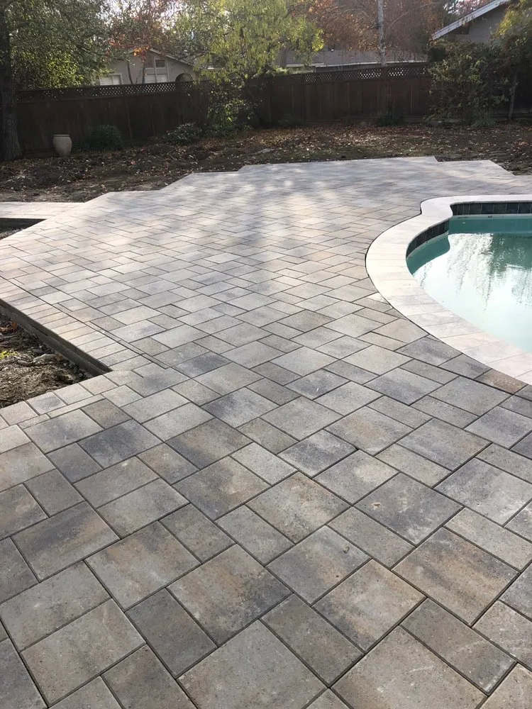 Picture of A seamless stone patio gracefully blends with the poolside landscape, showcasing ARP Hardscape's commitment to quality outcomes. The textured surface invites you to explore the backyard retreat. Copyright ©2025 Diamond Certified Resource - ARP Hardscape