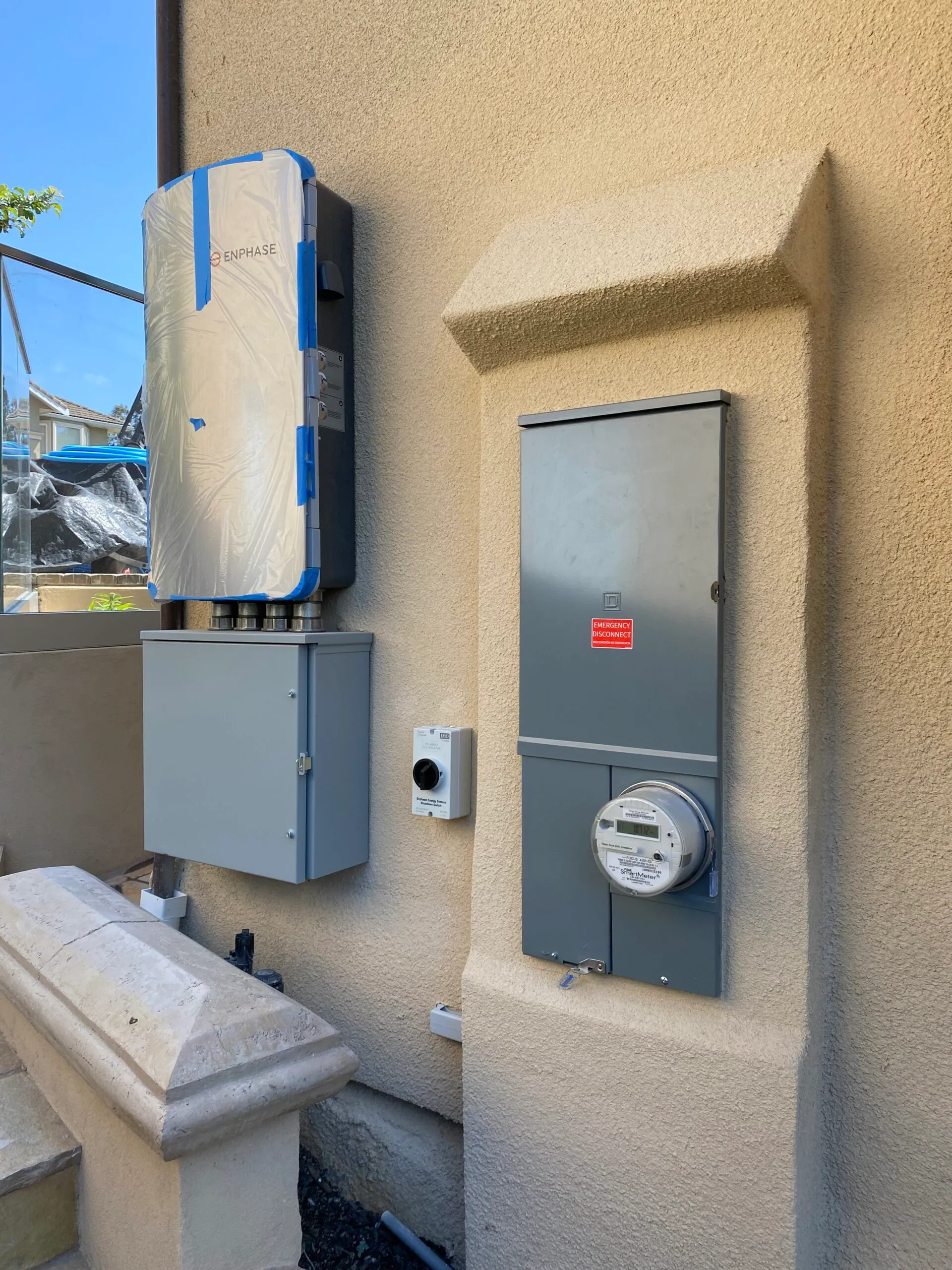  Enphase energy system on a beige wall, with electrical meter and boxes, showcasing precise installation by Century Roof and Solar.
