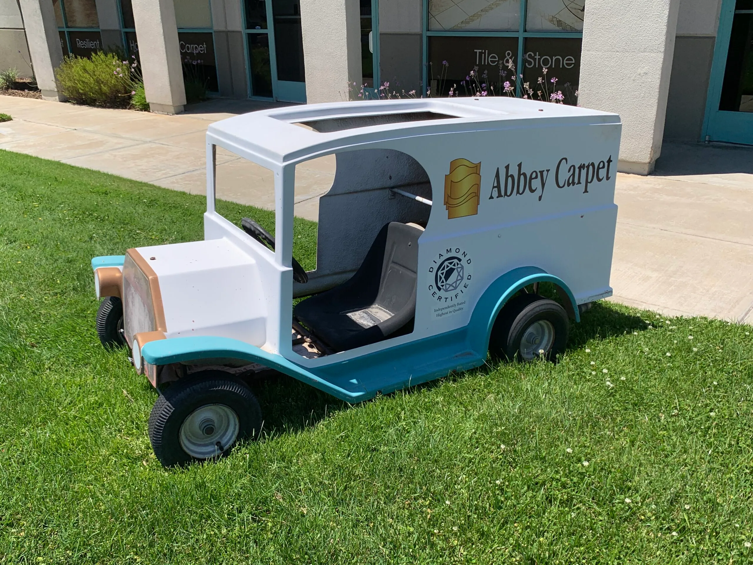 Picture of A charming miniature vehicle, branded with Abbey Carpets by Fashion Floors, sits on a lush green lawn, hinting at a playful and inviting approach to their showroom experience. Known for focusing on quality outcomes, the company invites you to explore their exceptional flooring options. Copyright ©2025 Diamond Certified Resource

 - Abbey Carpets by Fashion Floors