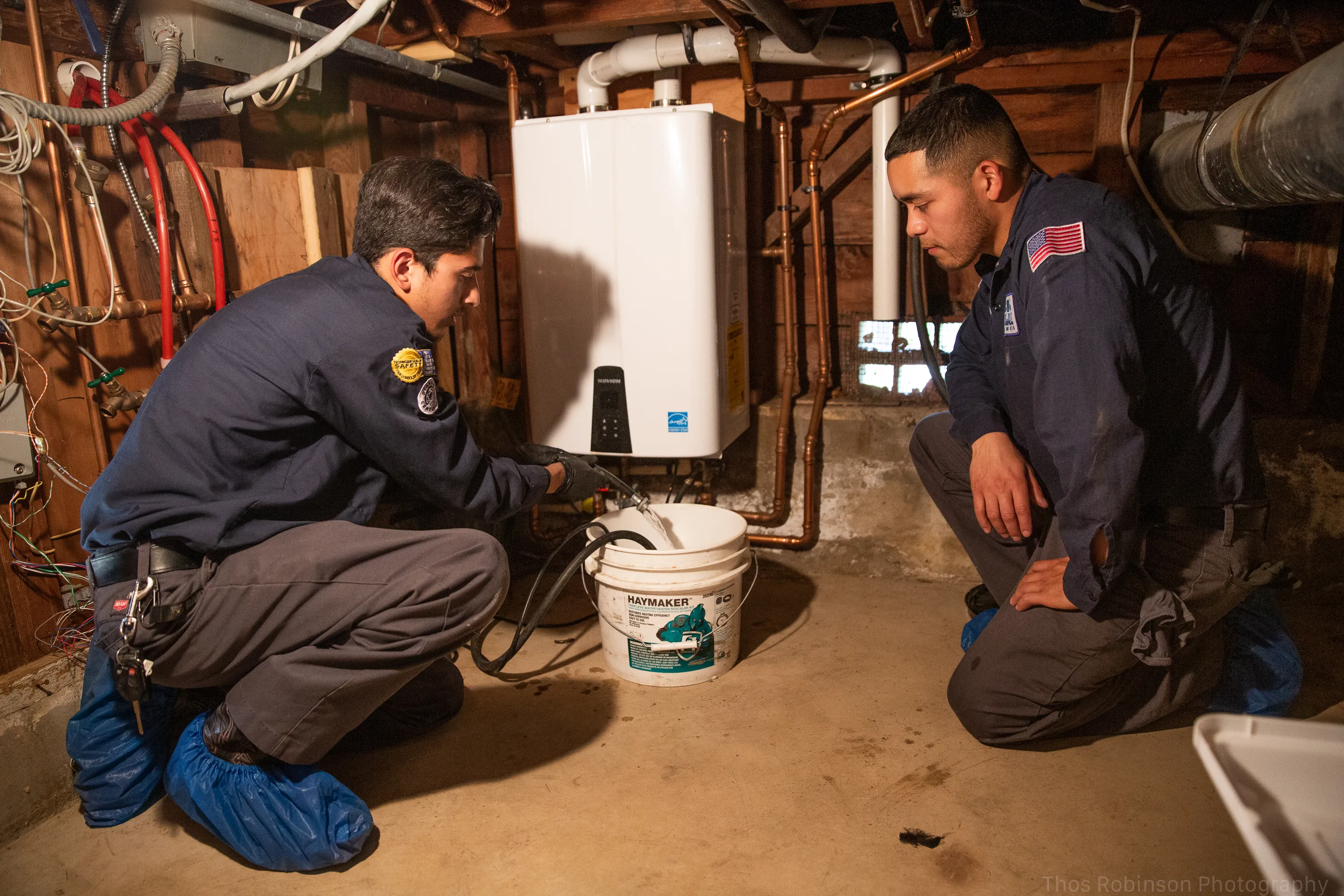 Picture of In a quiet basement, two technicians from Big Blue Plumbing focus intently on a tankless water heater, embodying precision and quality outcomes. The company consistently achieves a Highest in Quality rating. Copyright ©2025 Diamond Certified Resource

 - Big Blue Plumbing