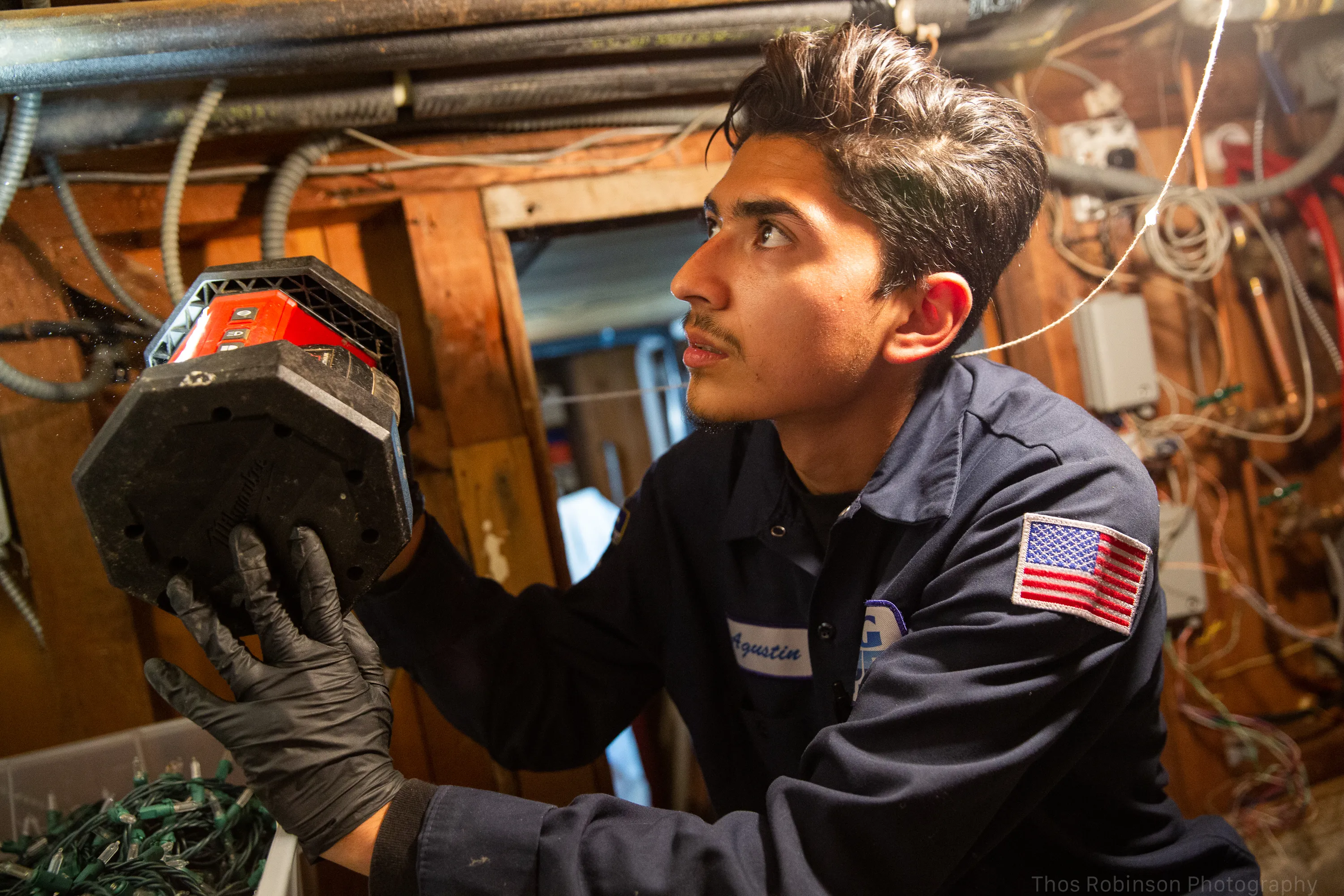 Picture of A Big Blue Plumbing technician carefully inspects a circuit in a dimly lit utility space, highlighting the companyâ€™s commitment to quality outcomes. Recognized for its expertise and quality, Big Blue Plumbing ensures every detail is meticulously checked. Copyright ©2025 Diamond Certified Resource

 - Big Blue Plumbing