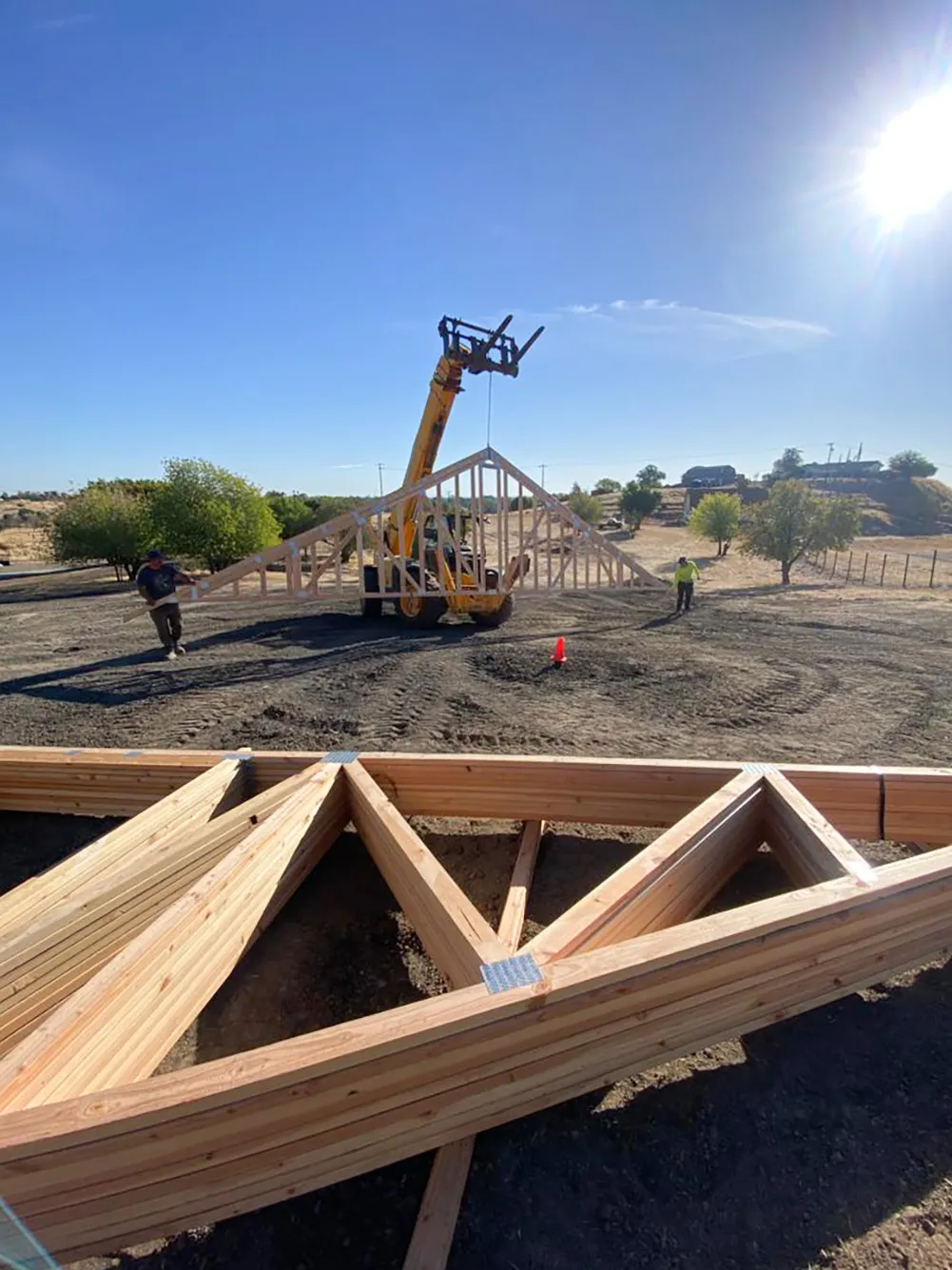 Picture of Under the bright sun, a crane deftly positions a massive truss as two workers guide it into place, showcasing Mana Construction Inc.'s commitment to quality outcomes. Recognized for expertise and quality, Mana Construction ensures every structural element is precisely aligned. Copyright ©2025 Diamond Certified Resource

 - Mana Construction Inc.